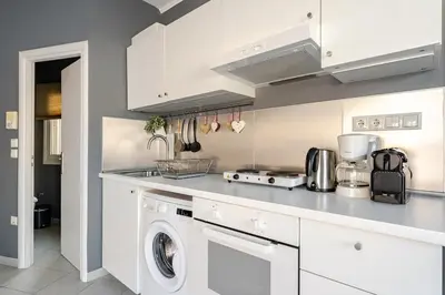 a kitchen with white cabinets and a washer and dryer at Lovely APT w/heated Jacuzzi &full Acropolis view in Athens