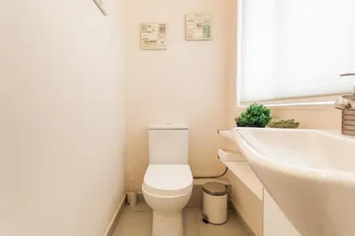 a bathroom with a white toilet and a sink at Lovely APT w/heated Jacuzzi &full Acropolis view in Athens