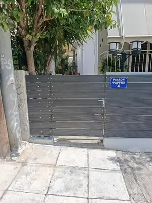 a gate with a blue sign in front of a house at Alimos Apartments in Athens