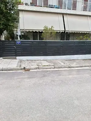 an empty street with a fence and a building at Alimos Apartments in Athens