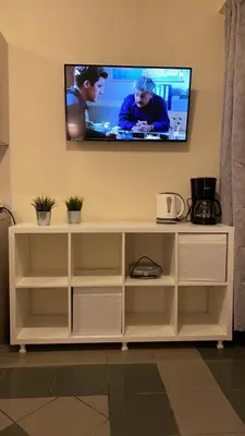 a white entertainment center with a television on a wall at Dina apartment in Athens