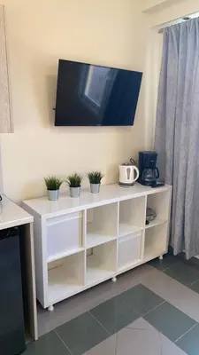 a white entertainment center with a tv on a wall at Dina apartment in Athens