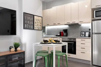 a kitchen with a white table and two green stools at New Apartment in the Heart of Plaka in Athens