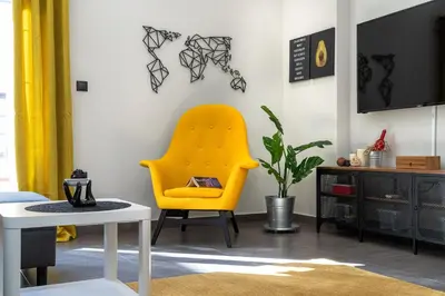 a yellow chair in a living room with a table at New Apartment in the Heart of Plaka in Athens