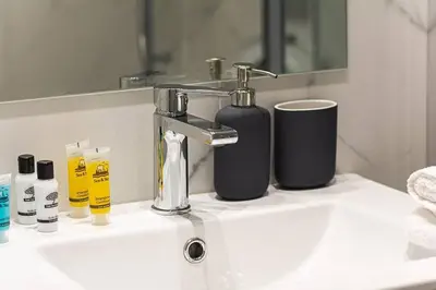 a bathroom sink with two bottles of soap and a mirror at A11 Pristine & comfy studio near Plaka & Parthenon in Athens