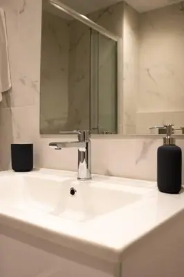a white bathroom sink with a mirror and a faucet at A11 Pristine & comfy studio near Plaka & Parthenon in Athens
