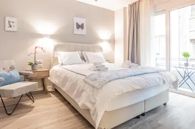 a white bedroom with a large bed and a window at A13 Pristine & Sunny 30m2 flat near Syntagma sq in Athens