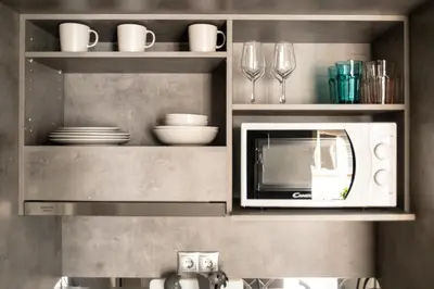 a kitchen with a microwave and plates and glasses at A13 Pristine & Sunny 30m2 flat near Syntagma sq in Athens