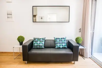 a black leather couch in a living room with a mirror at A22 Premium flat with balcony in the centre in Athens