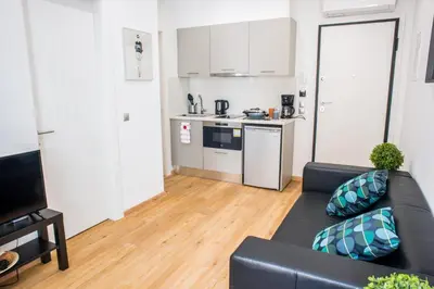 a living room with a black couch and a kitchen at A22 Premium flat with balcony in the centre in Athens