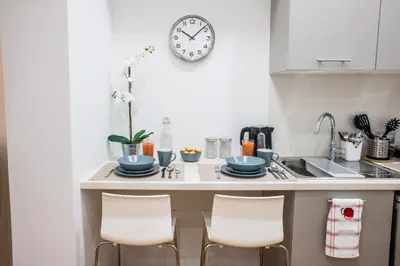 a kitchen with a counter with chairs and a clock on the wall at A21 Premium Suite a breath away from Parthenon! in Athens