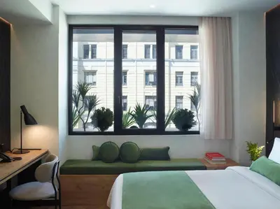 a bedroom with a bed and a window with plants at The Port Square Hotel in Piraeus