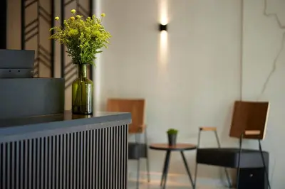 a vase of yellow flowers on a counter with chairs at The Port Square Hotel in Piraeus