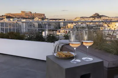 two glasses of wine and a basket of bread on a table at NEW STUNNING PENTHOUSE W/SPECTACULAR VISTAS! in Athens