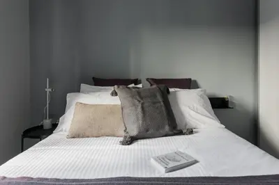 a bed with white sheets and pillows with a book on it at Unique 2BR Apartment in Filothei by UPSTREET in Athens