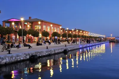 a group of people sitting next to a river at night at Seaside apartment in Flisvos marina in Athens