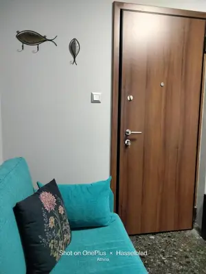a room with a blue couch and a wooden door at Modern-Lux Central 1 Bedroom Condo in Athens