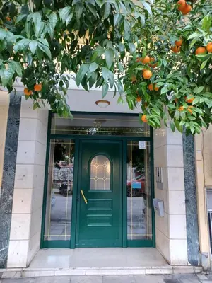 a green door in front of a building with an orange tree at Kallithea Gardenspot in Athens