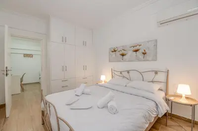 a white bedroom with a white bed with white pillows at Kallithea Gardenspot in Athens