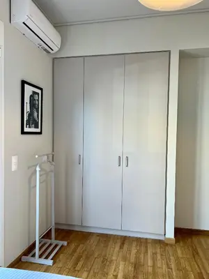 a white wardrobe in a bedroom with wooden floors at Mrs Holiday Apartment in Athens