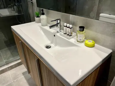 a white sink in a bathroom with a shower at Mrs Holiday Apartment in Athens