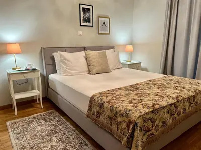 a bedroom with a bed and a table with two lamps at Mrs Holiday Apartment in Athens