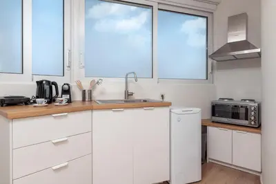 a kitchen with white cabinets and a sink and two windows at Athens Loft by Phoenix Apartments in Athens