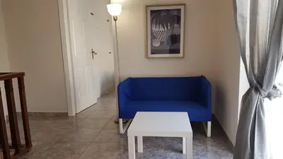 a blue couch in a living room with a table at Maisonaitte-Athens Center, 4 BD, 2 BATH in Athens