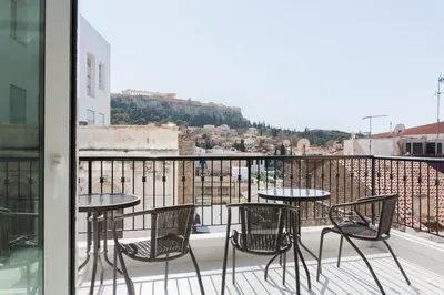 a patio with tables and chairs on a balcony at Athens Observatory Suite in Athens