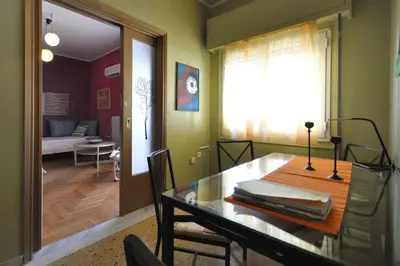 a dining room with a table and a living room at Nice Apartment Near City Center in Athens