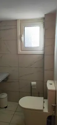 a bathroom with a toilet and a window at Nice Apartment Near City Center in Athens