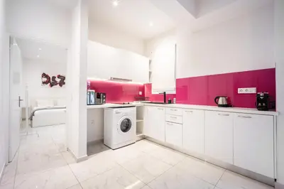 a white kitchen with pink walls and a washing machine at Cozy apartment in the center of Athens in Athens