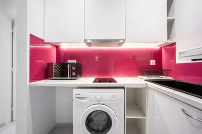 a kitchen with pink walls and a washing machine at Cozy apartment in the center of Athens in Athens