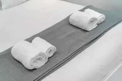 two rolls of white towels sitting on a bed at Cozy apartment in the center of Athens in Athens