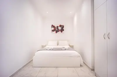 a white bedroom with a white bed and a mirror at Cozy apartment in the center of Athens in Athens