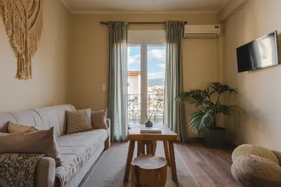 a living room with a couch and a large window at Living Stone Aparthotel in Athens