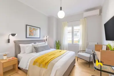 a bedroom with a bed and a tv and a chair at Sun-Splashed 2-BDR Corner Apartment with Hillside views! in Athens