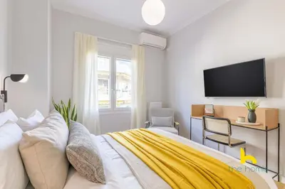 a bedroom with a bed and a tv on the wall at Sun-Splashed 2-BDR Corner Apartment with Hillside views! in Athens