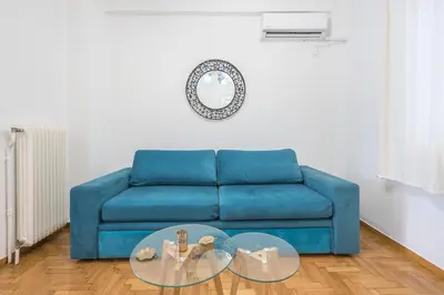 a blue couch in a living room with a glass table at Athens Dreams & Suites Apartments in Athens