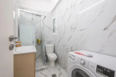 a white bathroom with a washing machine in it at Athens Dreams & Suites Apartments in Athens