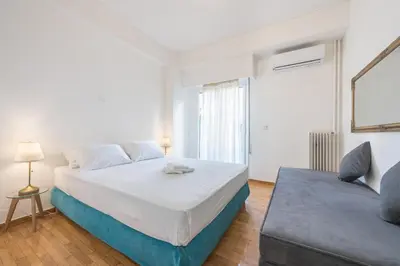 a white bedroom with a bed and a couch at Athens Dreams & Suites Apartments in Athens