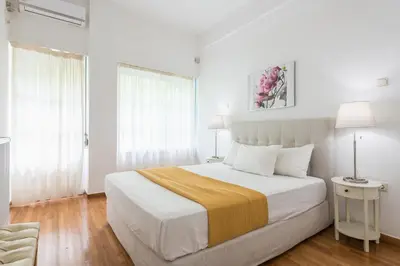 a white bedroom with a large bed and two lamps at Victoria Prestige Suites Apartments in Athens