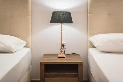 a lamp on a table between two beds at Victoria Prestige Suites Apartments in Athens