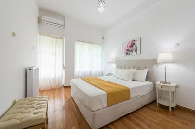 a bedroom with a large bed with white walls and wooden floors at Victoria Prestige Suites Apartments in Athens