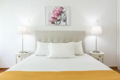 a bedroom with a large white bed with two lamps at Victoria Prestige Suites Apartments in Athens