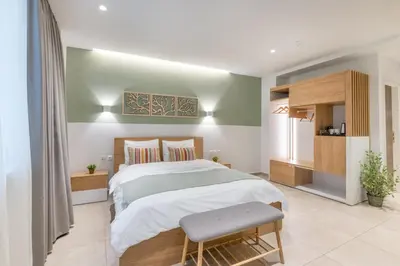 a bedroom with a large bed and a chair at STARLA STUDIOS in Athens