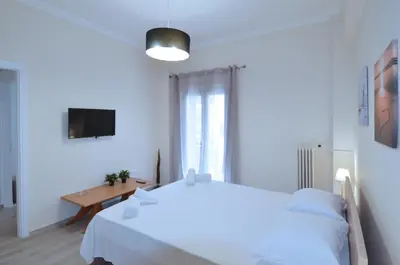 a white bedroom with a white bed and a table at A heart apartment at Skouze Hill, Dirrachiou in Athens
