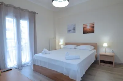 a white bedroom with a large bed with white sheets at A heart apartment at Skouze Hill, Dirrachiou in Athens