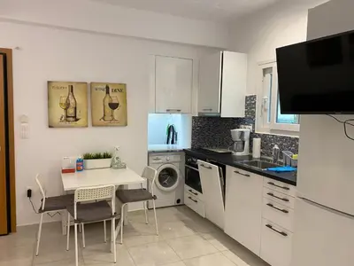 a white kitchen with a table and a sink at George House in Athens