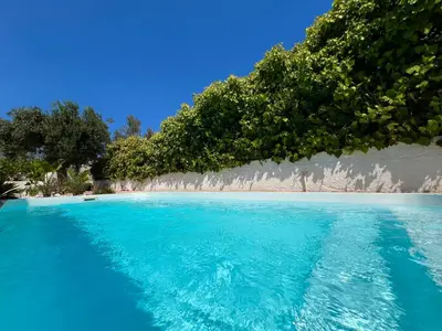 a pool of blue water with trees on a beach at Pool Villa Lagonisi 5min from Beach in Koropíon